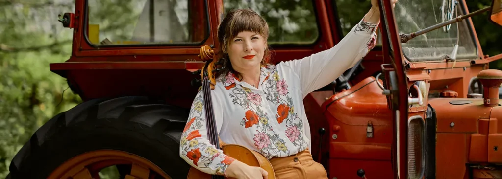 petronella with cello in front of an old volvo tractor